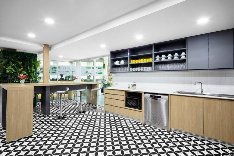 Modern communal kitchen at 7 Sukhumvit 69 Road featuring black and white patterned tile flooring.