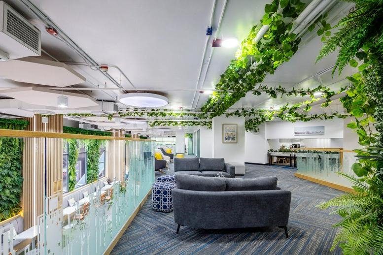 Bright coworking lounge at 7 Sukhumvit 69 Road with hanging ivy and grey sofas.