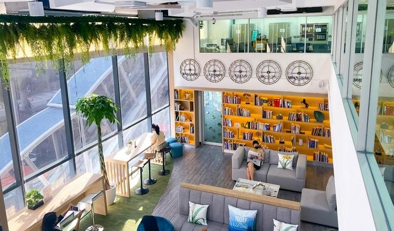 Modern coworking space at 7 Sukhumvit 69 Road featuring floor-to-ceiling windows and a library wall.