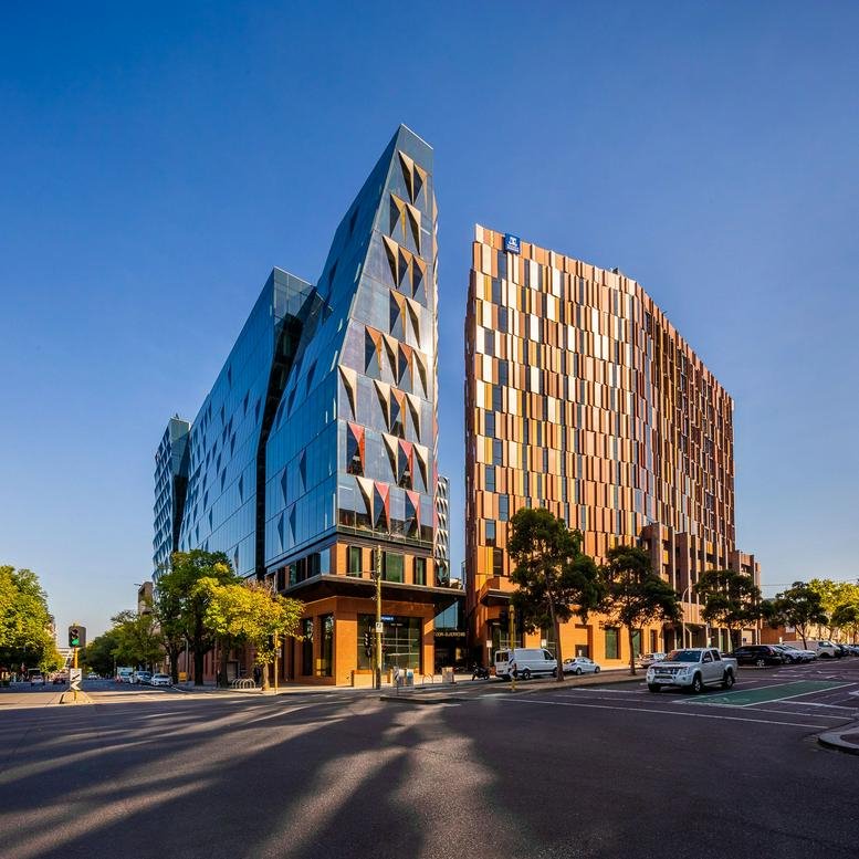 Exterior view of the modern glass-fronted 700 Swanston Street building under a clear blue sky.