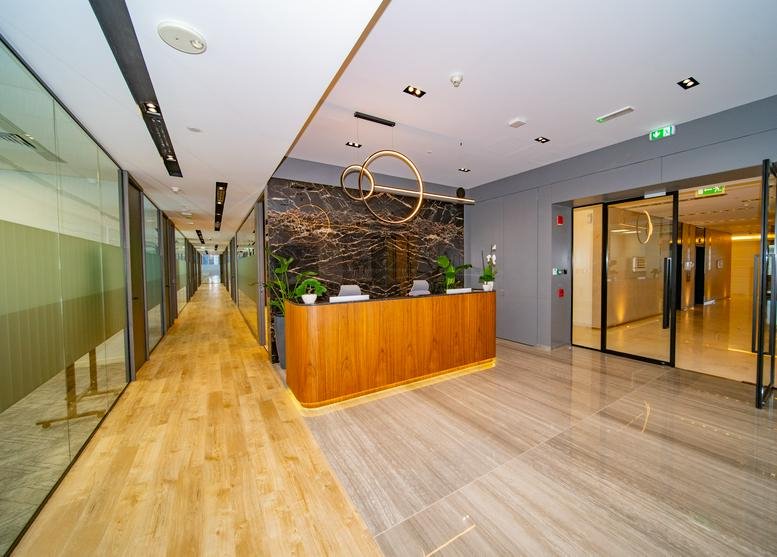 Professional reception area at Building 6, Emaar Square featuring a wood-fronted desk and marble walls.