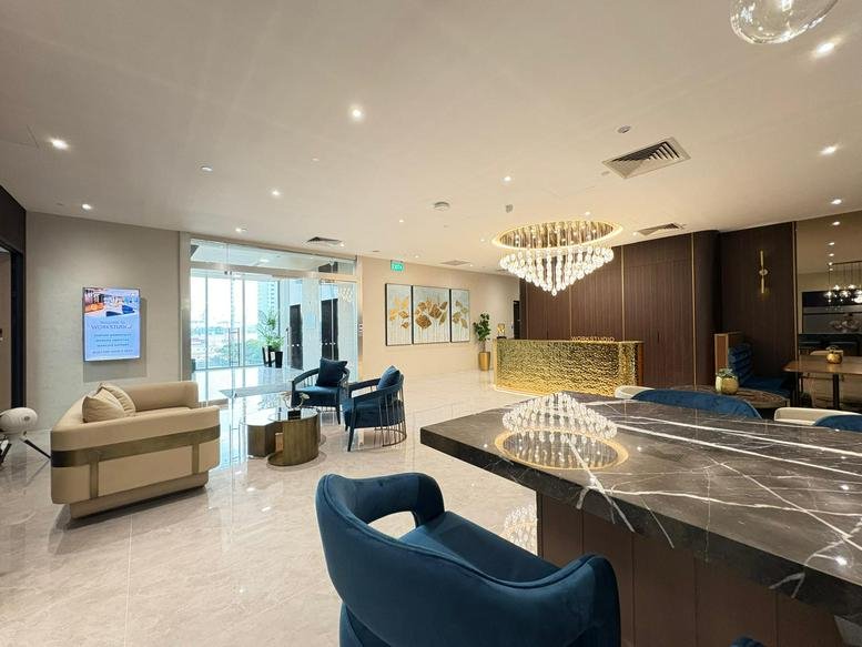 Luxurious reception and lounge area at 78 Shenton Way featuring gold accents, blue velvet chairs, and a chandelier.
