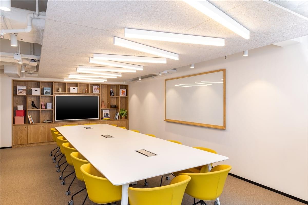Meeting room at 8 Queen's Road East with a long white table and bright yellow chairs.