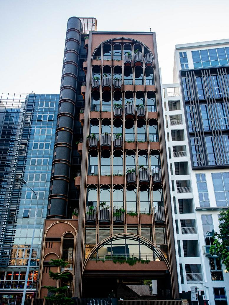 Modern exterior of the unique brown arched building at 81 Aljunied Road in Singapore.