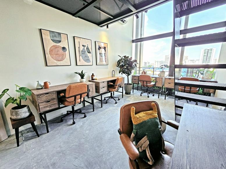 Sunlit open-plan office with timber desks, leather chairs, and large windows.