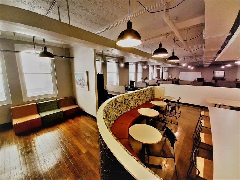 Meeting room with glass partitions, floral-patterned seating, and pendant lights.