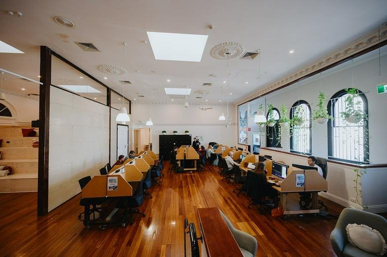Vibrant coworking space at 84A Brunswick Street with high ceilings, skylights, and rows of wooden desks.