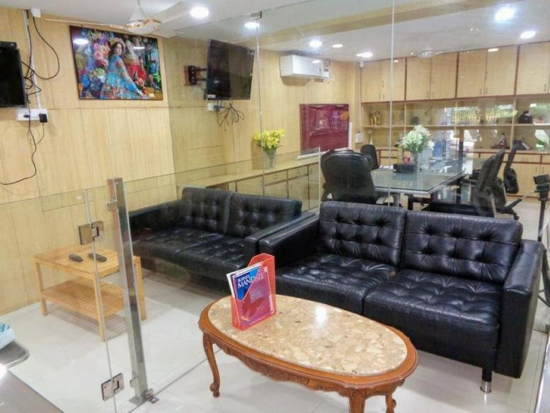 Reception and waiting area of Jagan Towers with black leather sofas and an oval coffee table.
