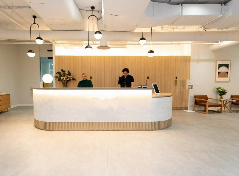 Modern curved reception desk at 89 Pirie Street with warm wood paneling and designer pendant lights.
