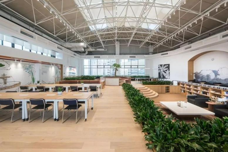 Bright, high-ceilinged open-plan workspace at Block A, Golden Eagle Center with industrial trusses and greenery.