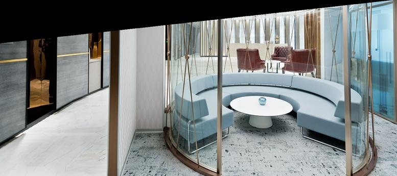 Spacious communal lounge at Prestige Technostar with curved light blue sofas and a glass-walled breakout area.