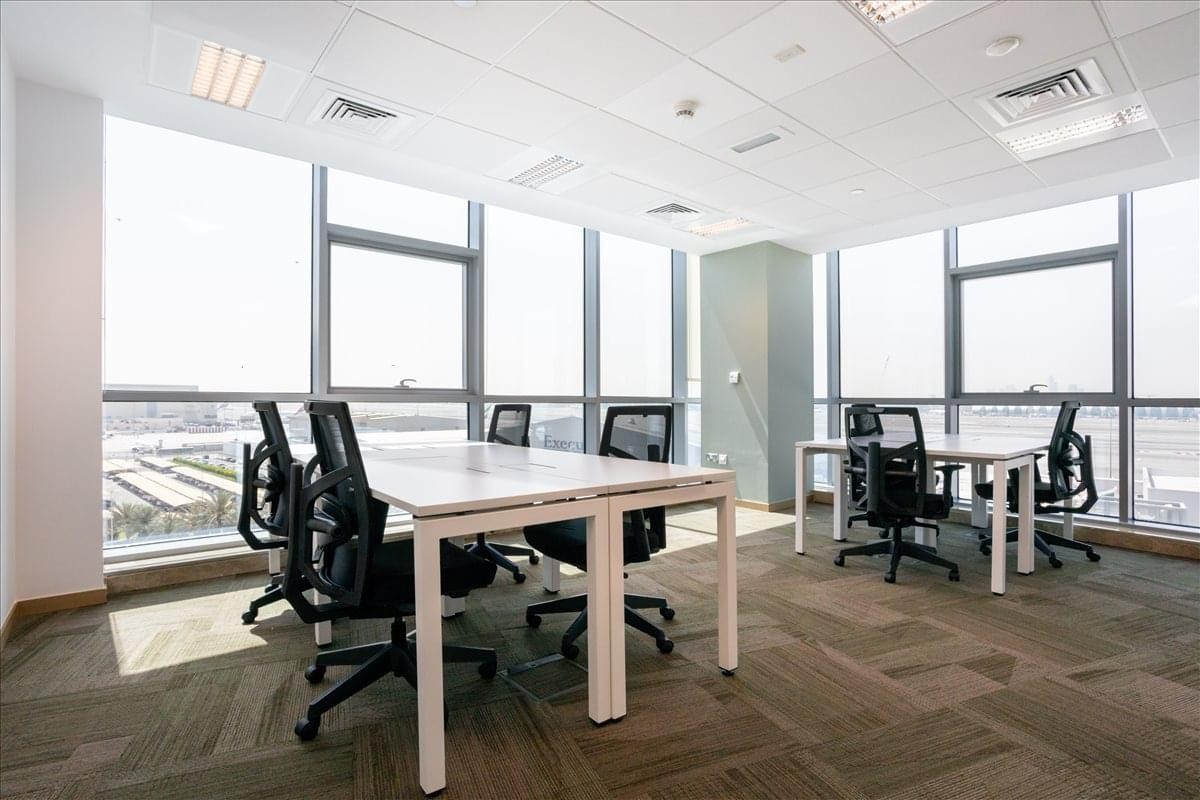 Spacious open-plan workspace at the 8W building featuring multiple white desks and large wrap-around windows.