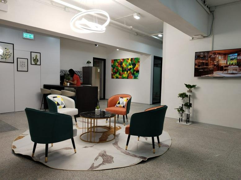 Spacious open-plan lounge with colorful seating, abstract art, and a large wall-mounted screen.