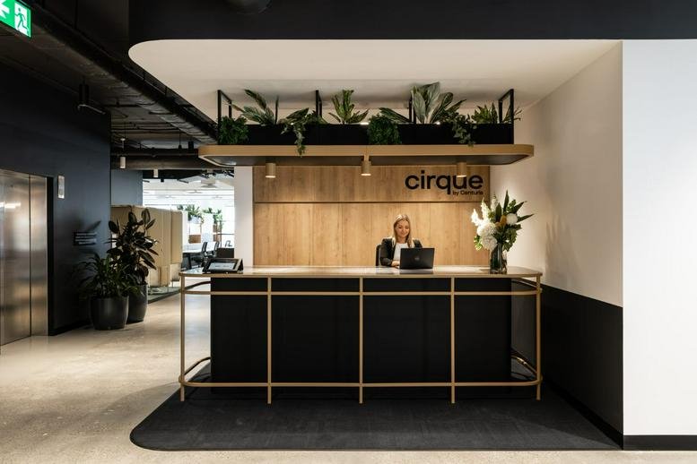 Reception area at 9 Help Street, Sydney, with wood paneling, hanging plants, and a black front desk.