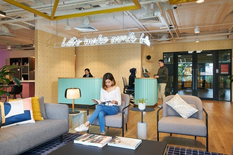 Bright reception area at 9 Tampines Grande with teal front desks and neon wall signage.