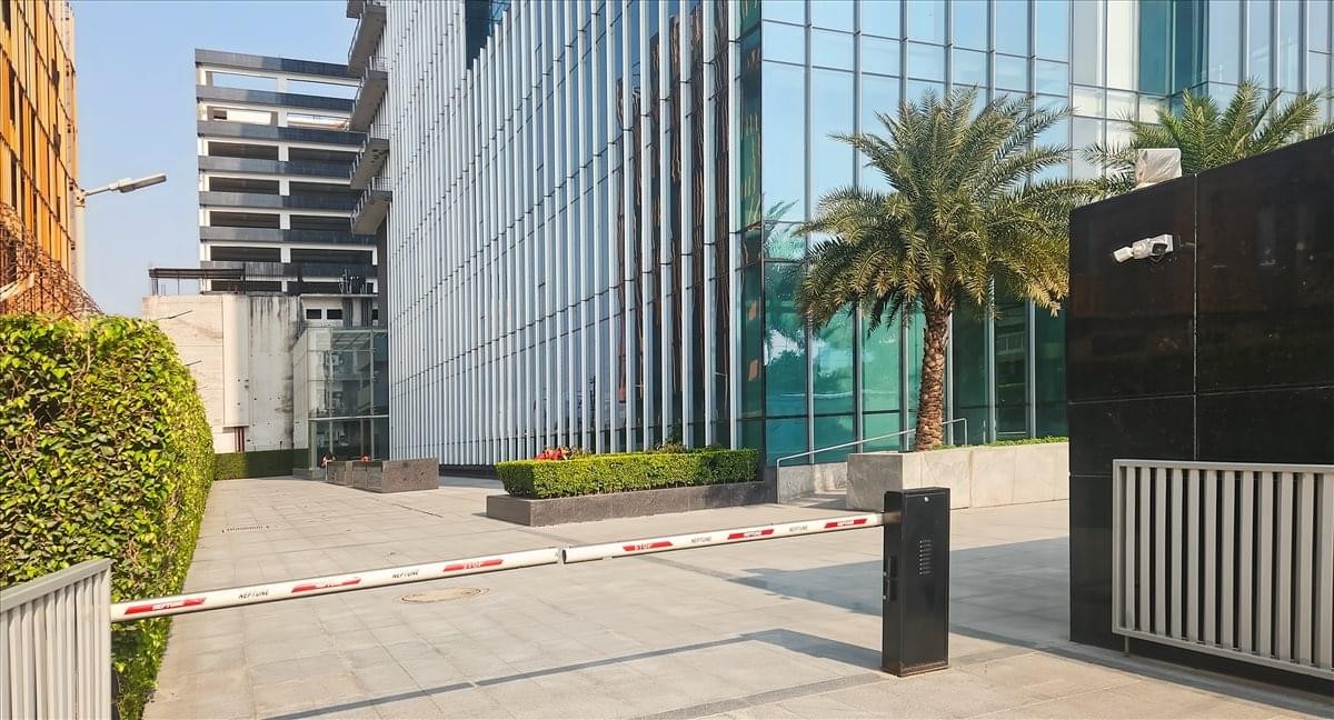 Modern glass exterior of the Sovereign Corporate Tower with a secure gated entrance and palm trees.