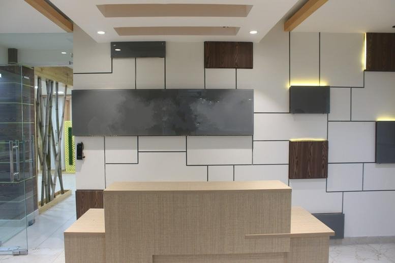Reception area at A-64, Sector-63, Noida, India with a modern wood desk and geometric wall pattern.