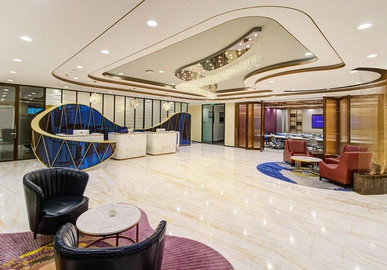 Spacious reception area with curved blue feature desk and wave-inspired ceiling at Parinee Crescenzo.