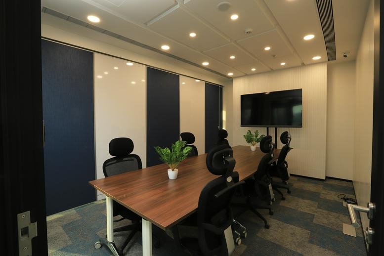Spacious boardroom at A Wing The Capital with dark blue accent walls and a wooden table.
