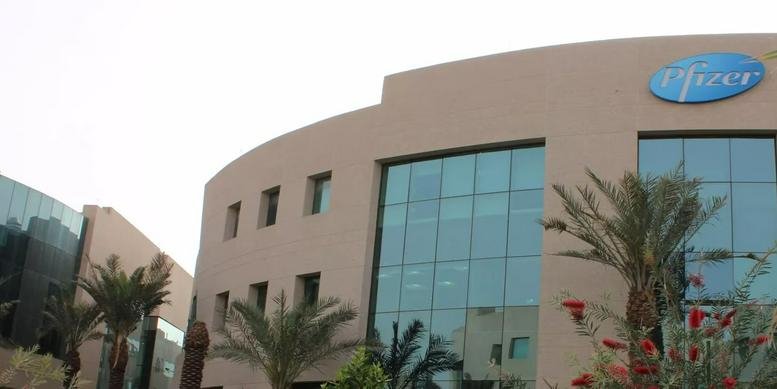 Exterior view of Building No. 7 at The Business Gate, Zone A featuring a curved facade and palm trees.