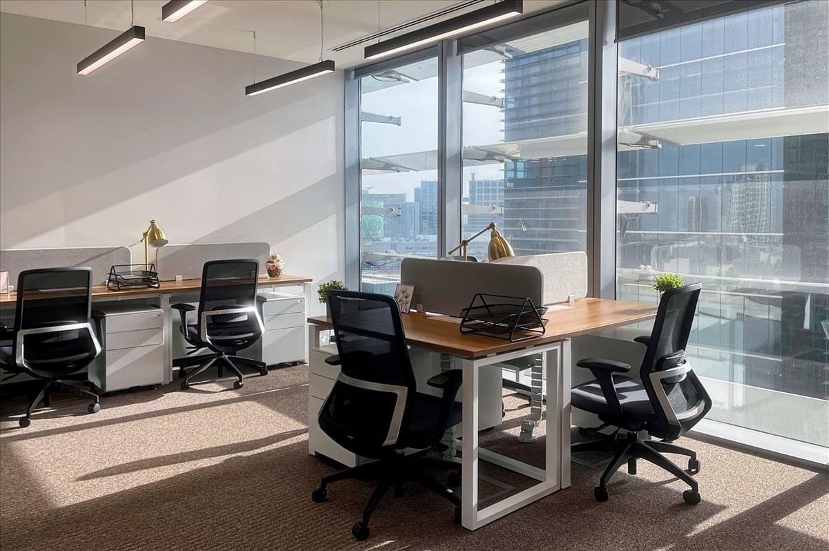 Spacious open-plan workspace at Al Maqam Tower with modern desks and floor-to-ceiling windows.