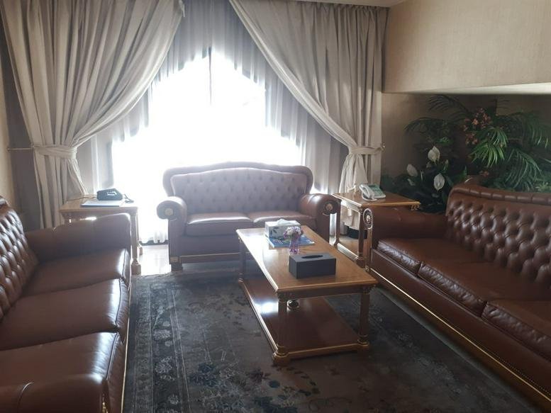 Spacious reception area at Al Nasr Street, Abu Dhabi with classic furniture, a wooden sideboard, and framed art.