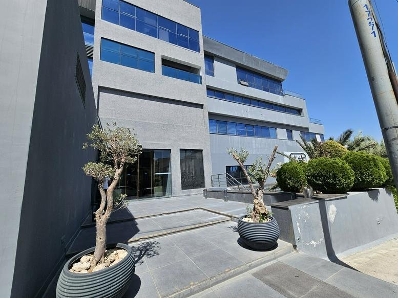 Sleek office building facade at Al Shajarah Street, Amman with grey cladding and large windows.
