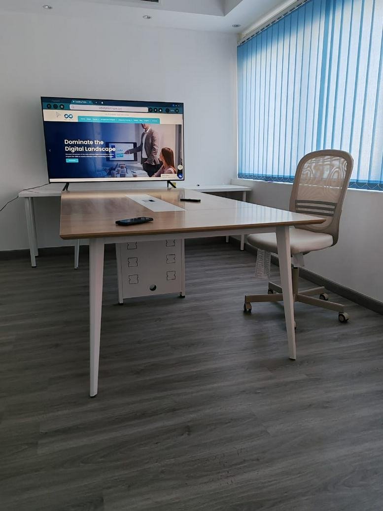 Bright private office featuring a large wall-mounted monitor and wooden desk at Al Sharq Street, Al Naba’a.