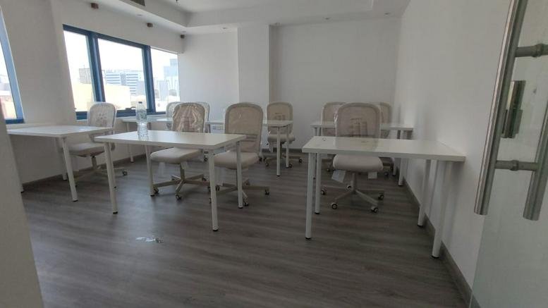 Multiple white desks and mesh chairs in a bright training or meeting room at Al Sharq Street, Al Naba’a.