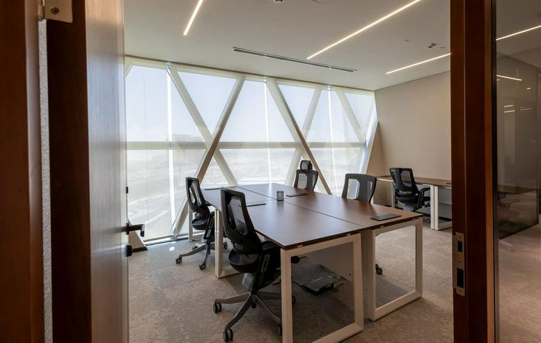 Bright private office suite with shared desks and views through geometric windows.