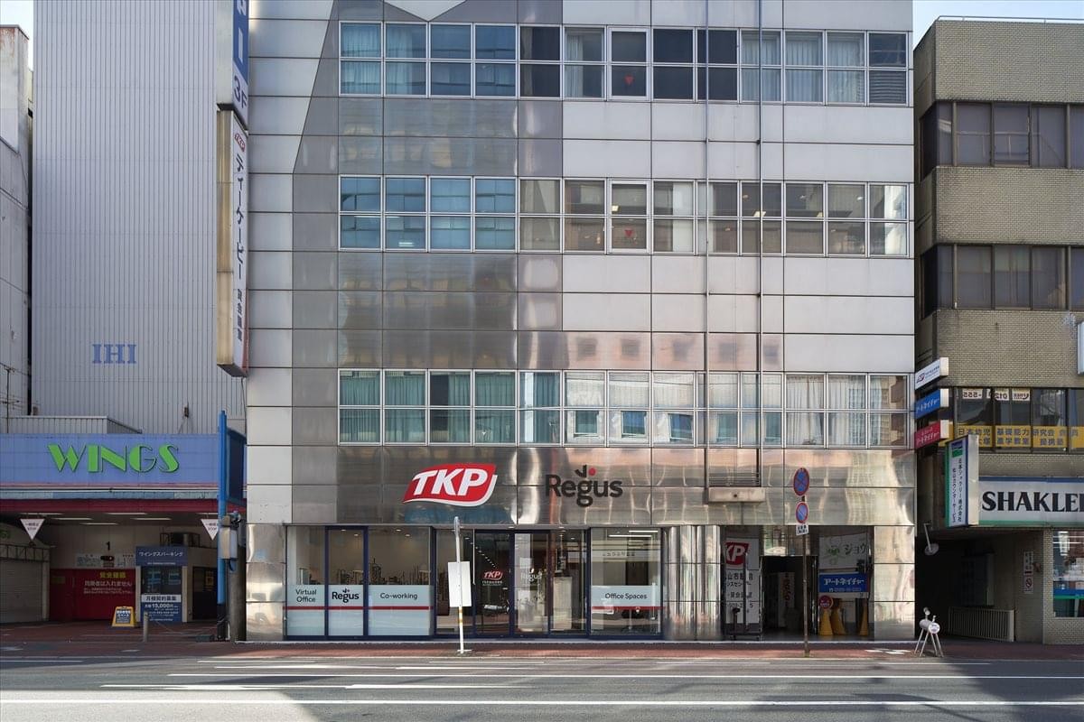 Exterior view of the Aono Building 1F featuring a modern multi-story glass facade and street-level entrance.