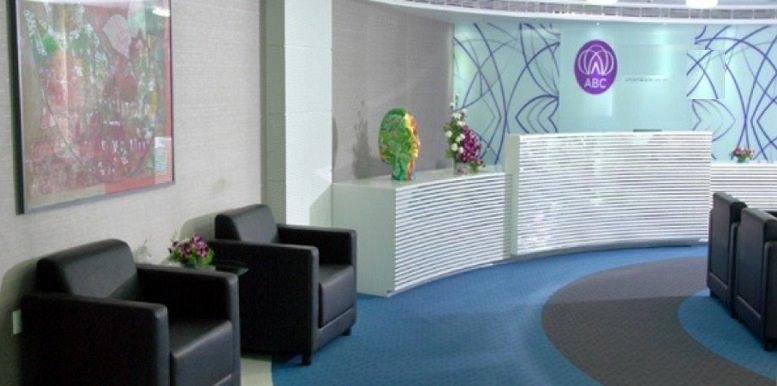 Spacious reception area with a white textured desk, blue carpet, and stylish leather armchairs.