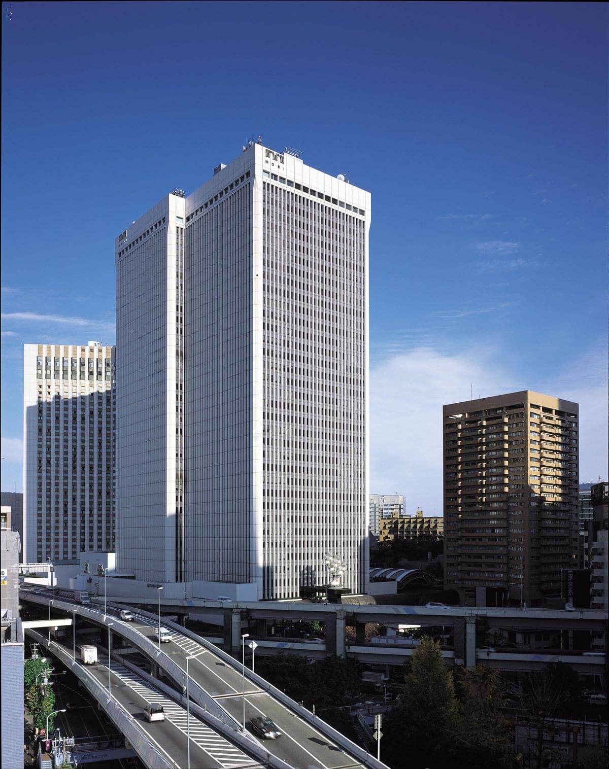Exterior view of the white high-rise ARK Mori Building overlooking city highways.