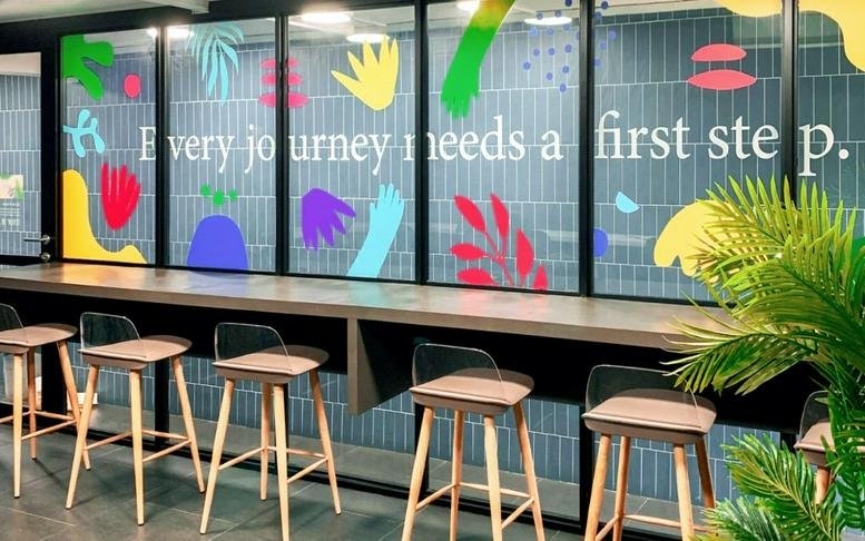 Modern coworking area at Assemblage, 362 Holland Road with high stools and a colorful graphic feature wall.