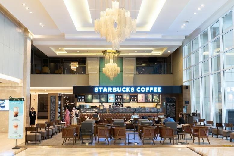 Spacious lobby with a Starbucks coffee counter and elegant chandeliers.