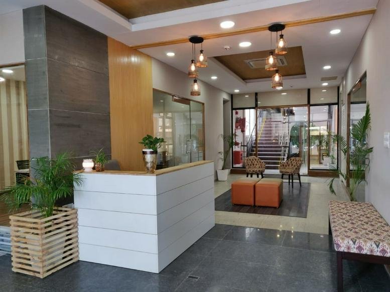 Bright reception area featuring a white slatted desk, wooden accents, and hanging bulb lights.