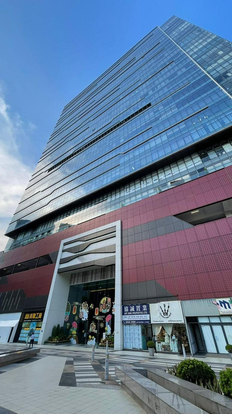 Low-angle exterior view of the glass-facade TML Tower against a blue sky.