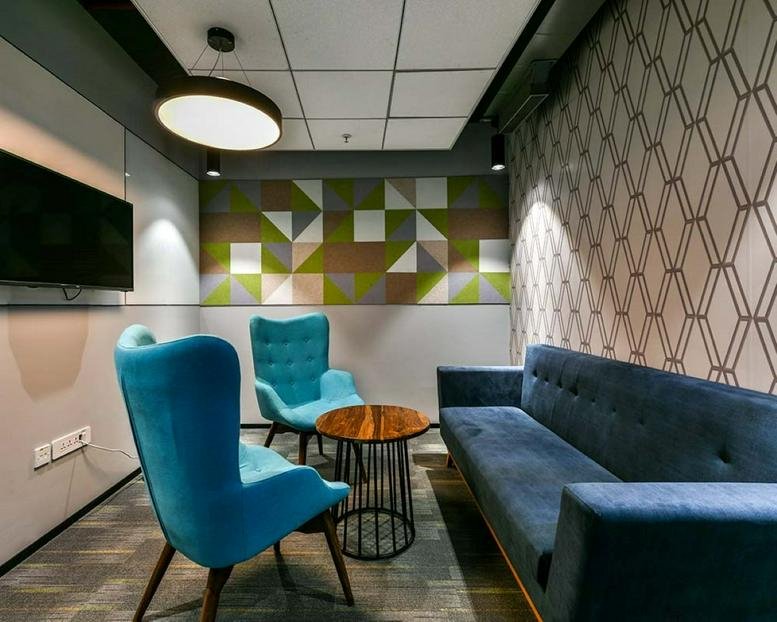 Colorful lounge area at Bascon Futura SV IT Park with teal armchairs and geometric wall art.