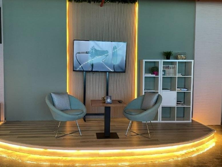 Spacious lounge area at Baseel Tower featuring light blue armchairs and a warm wood-slatted feature wall.