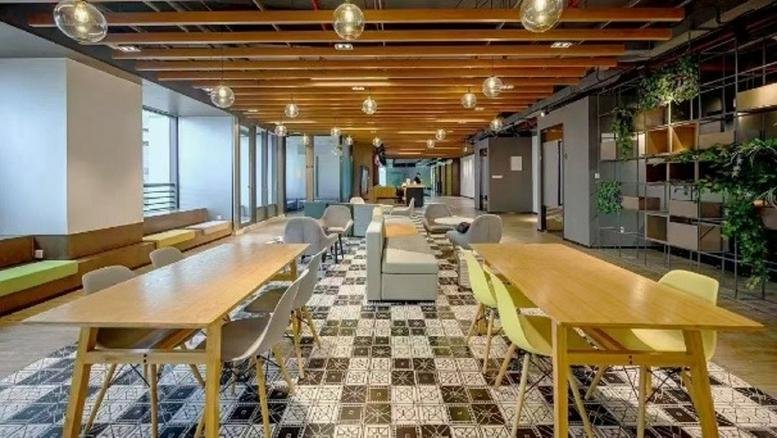 Spacious communal lounge and coworking area at Leyi Haichuang Building with wooden ceilings and modern lighting.