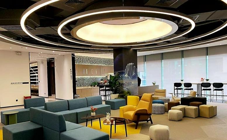Spacious lounge at Kaisa Center with colorful armchairs and a dramatic circular ceiling light installation.
