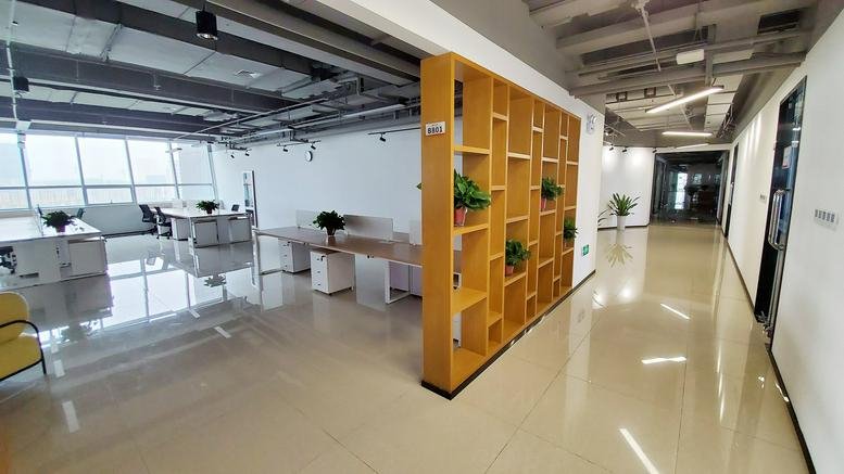 Spacious interior at Yunwei International Building featuring a wooden bookshelf divider and open-plan desks.