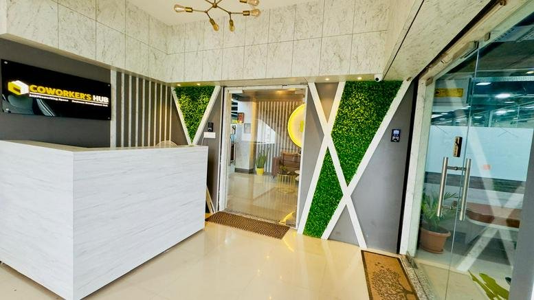 Spacious reception area of Coworker's Hub in the BS Tower with white front desk and green feature walls.