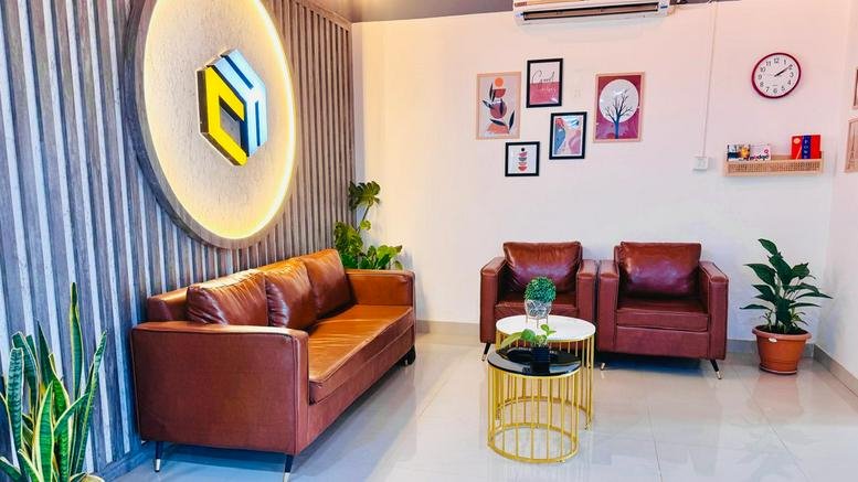 Communal lounge area featuring brown leather seating, wall art, and indoor plants.