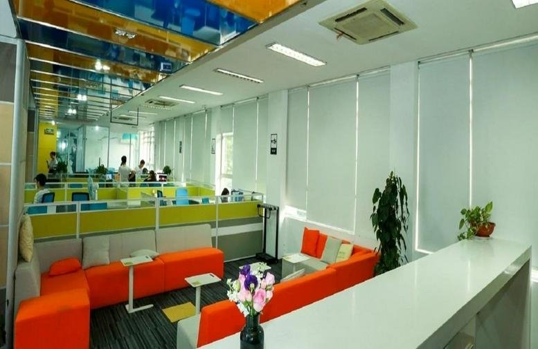 Colorful reception and lobby area with orange modular sofas and bright ceiling panels.