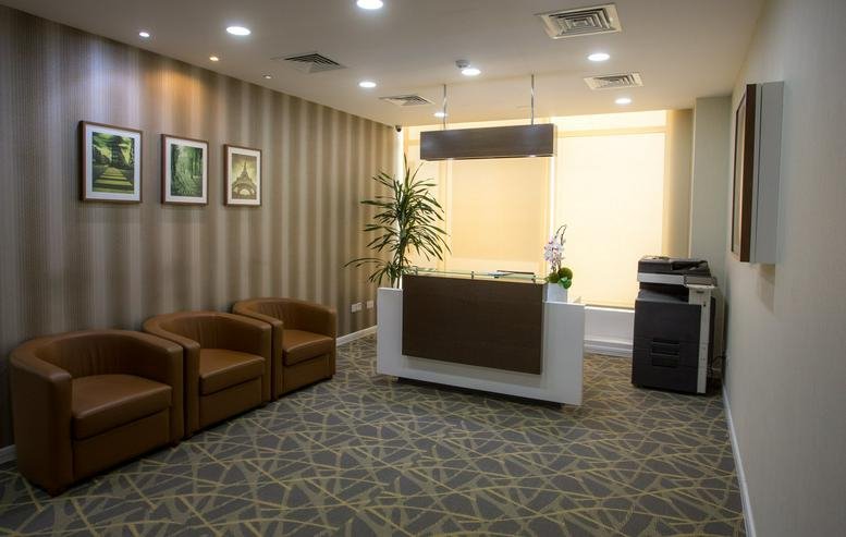 Reception area at Building 311, C Ring Road, Doha with brown leather armchairs and striped wallpaper.