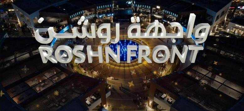 Exterior night view showing the illuminated entrance signage of Roshn Front in Riyadh.