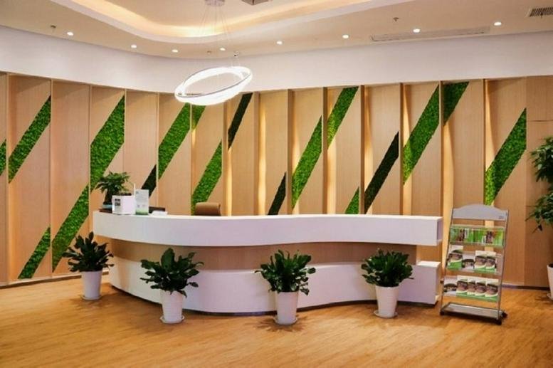 Bright reception desk at Hanyang Renxinhui Building C featuring a curved white counter and green moss wall panels.