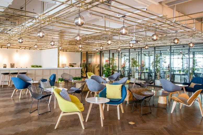 Spacious communal lounge at Building ICC-T2, Kaisa, featuring colorful chairs and decorative overhead piping.