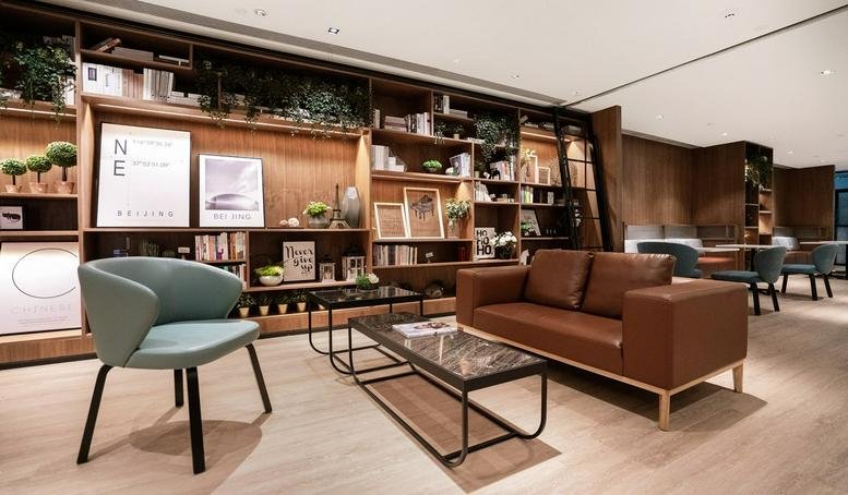 Spacious lounge at Building M6, ICP Huanhui Commercial Plaza with a brown leather sofa and wooden bookshelves.